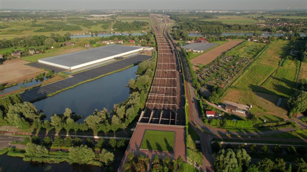 Dronebeeld van Barendrecht met het spoor, kassen en volkstuinen