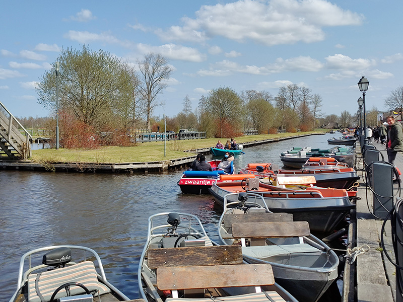 Verhuurboten liggen aangemeerd langs de gracht in Giethoorn op een zonnige dag.