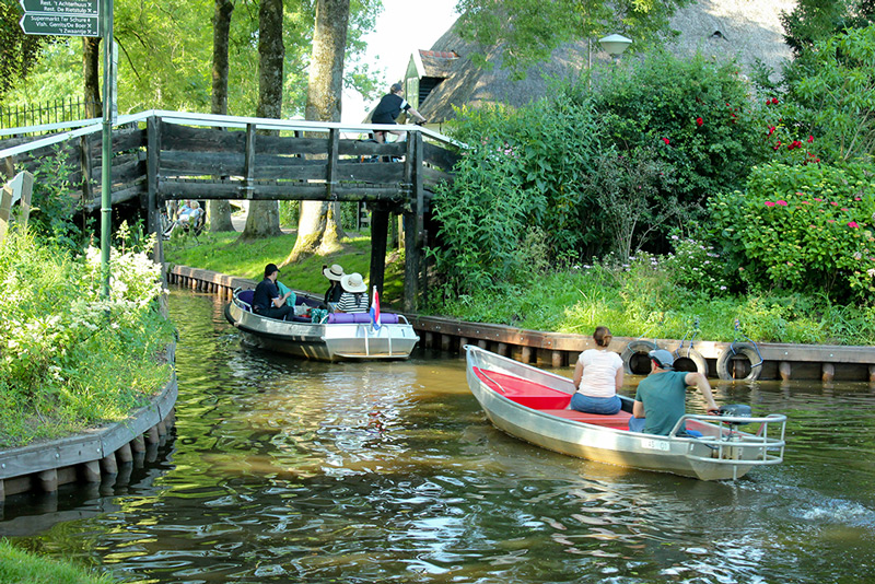 Mensen varen met bootjes door de gracht in Giethoorn.
