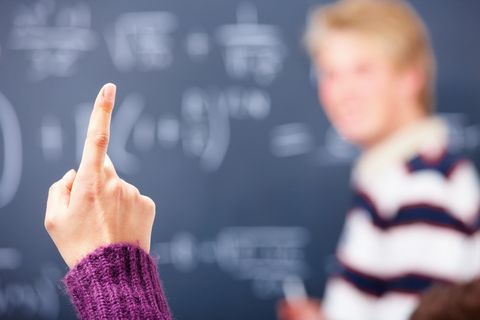 Leerling steekt vinger op in de klas als symbool voor onderwijs en gelijke kansen.